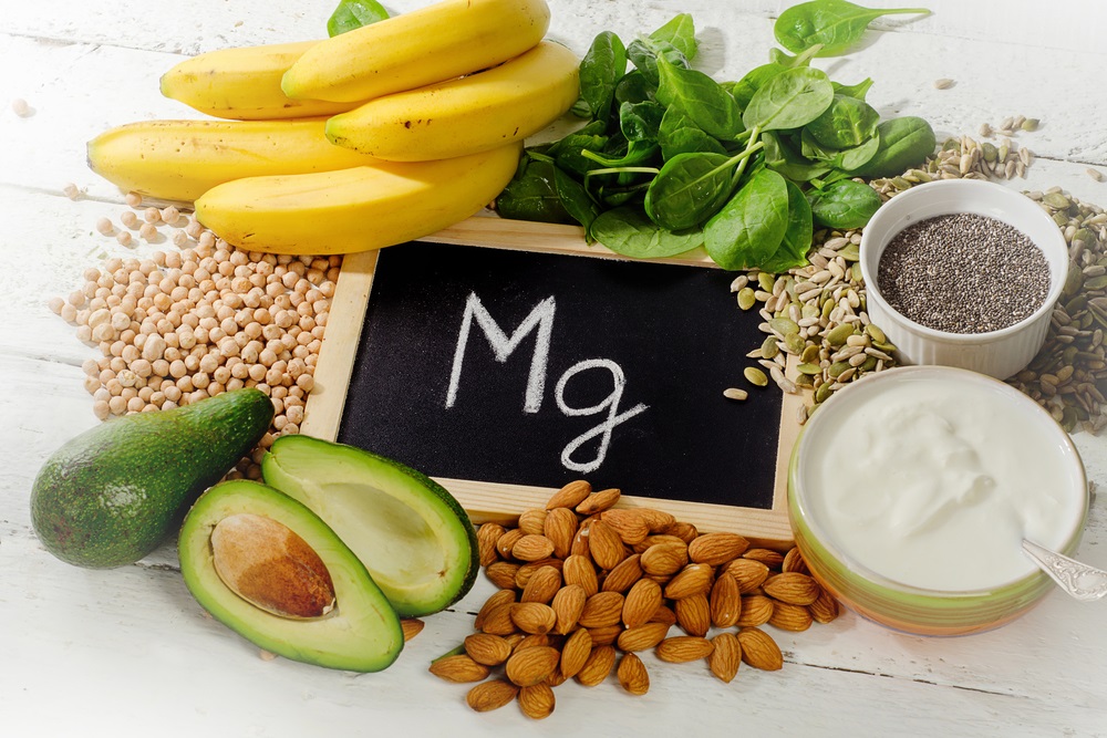 Products containing magnesium: bananas, almonds, avocado, nuts and spinach and eggs on table